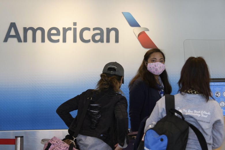 A masked American Airlines agent checks in travelers.