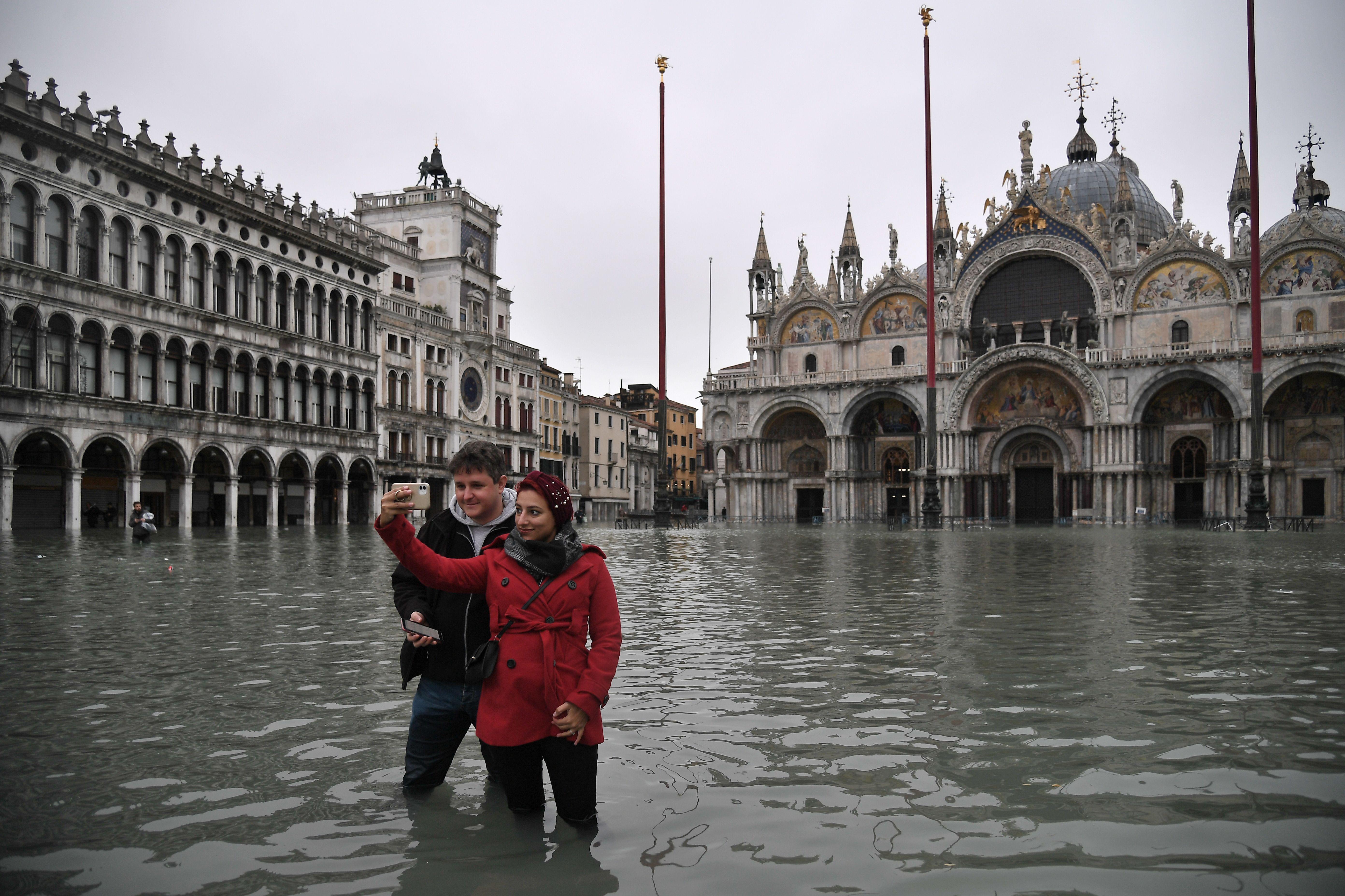 People take a selfie at the flooded St. Mark's Square. 