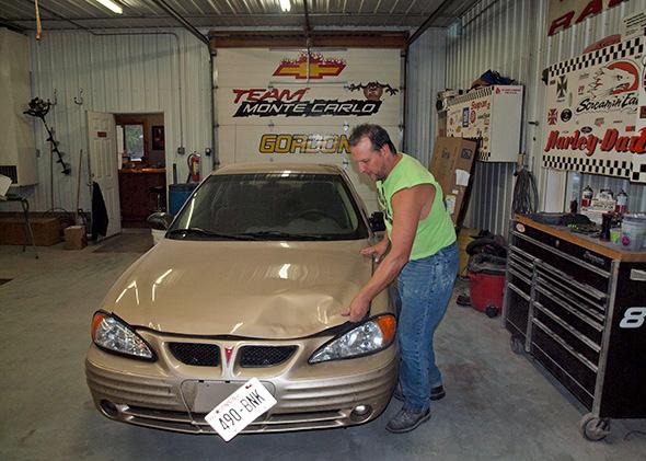 George Hertzner looks at a car damaged in a car-deer collision