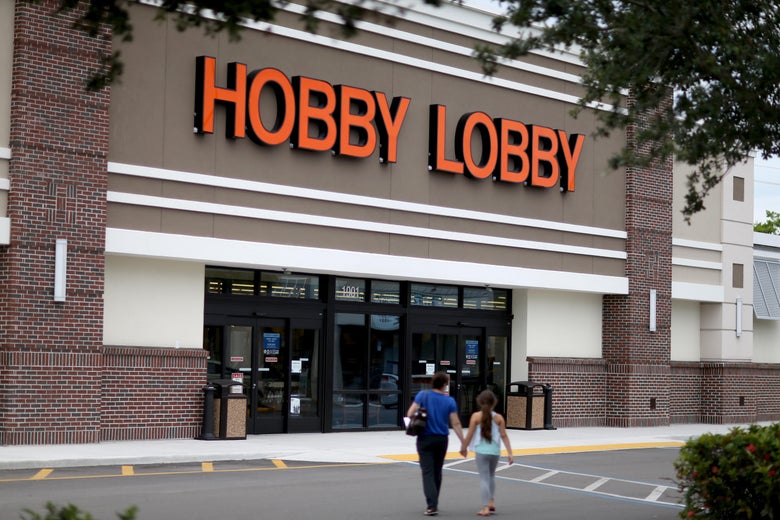 People walk across a parking lot into a Hobby Lobby store.