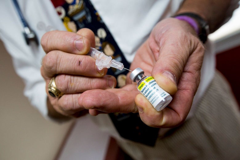 Close-up of Ohnmacht's hands as he uses a syringe to draw liquid out of a vial