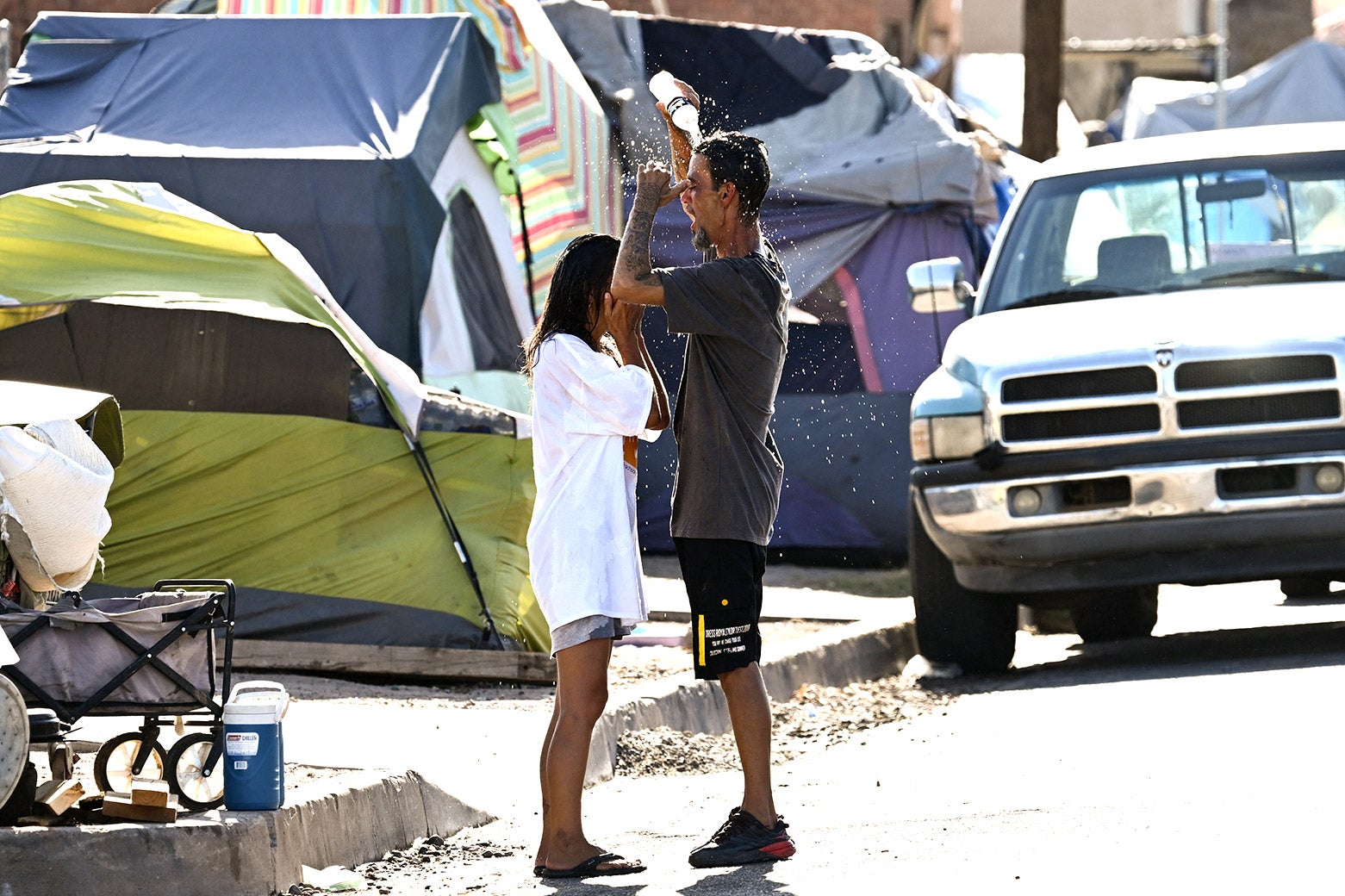 People pour water on themselves in front of tents in Phoenix.
