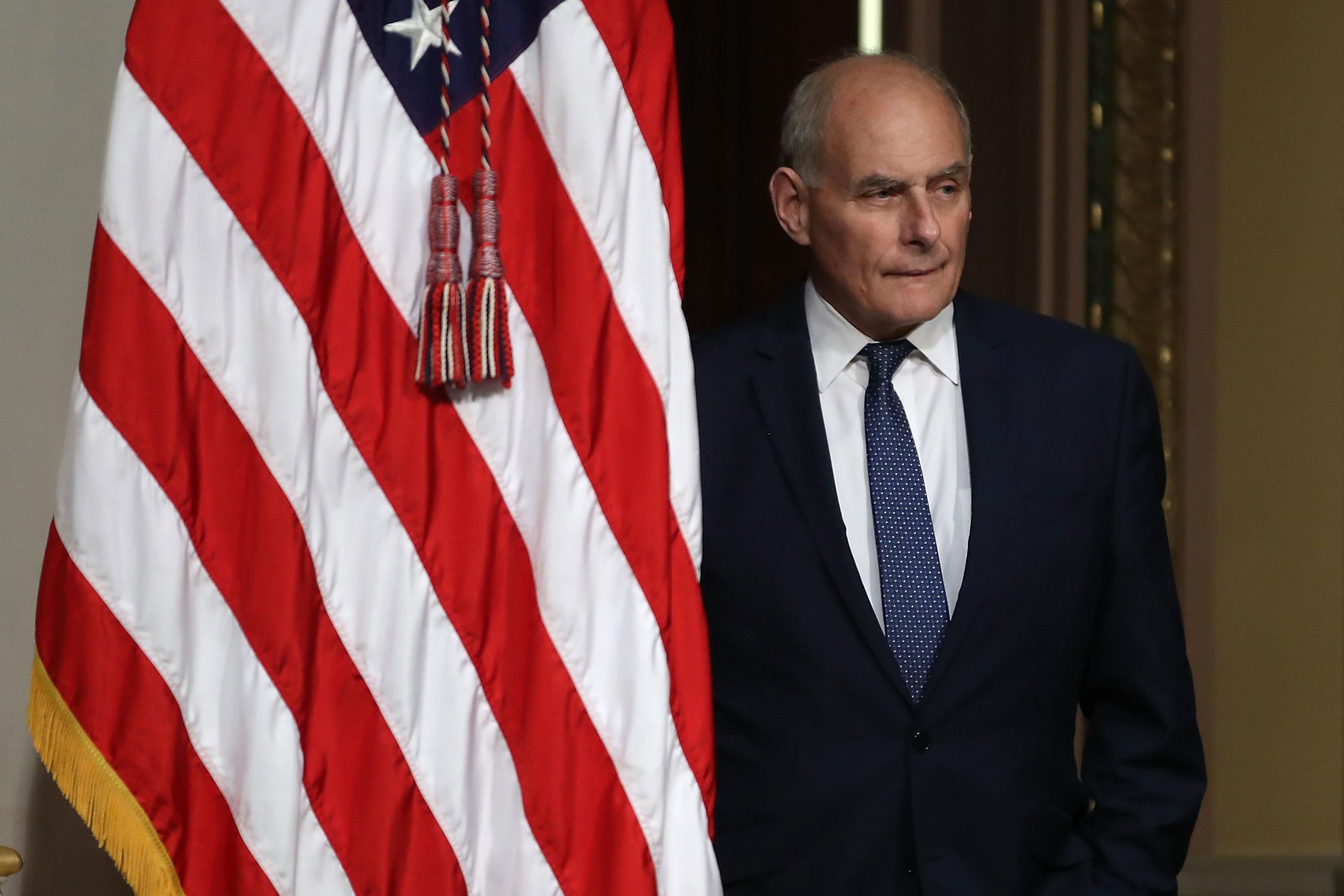 John Kelly stands next to an American flag.