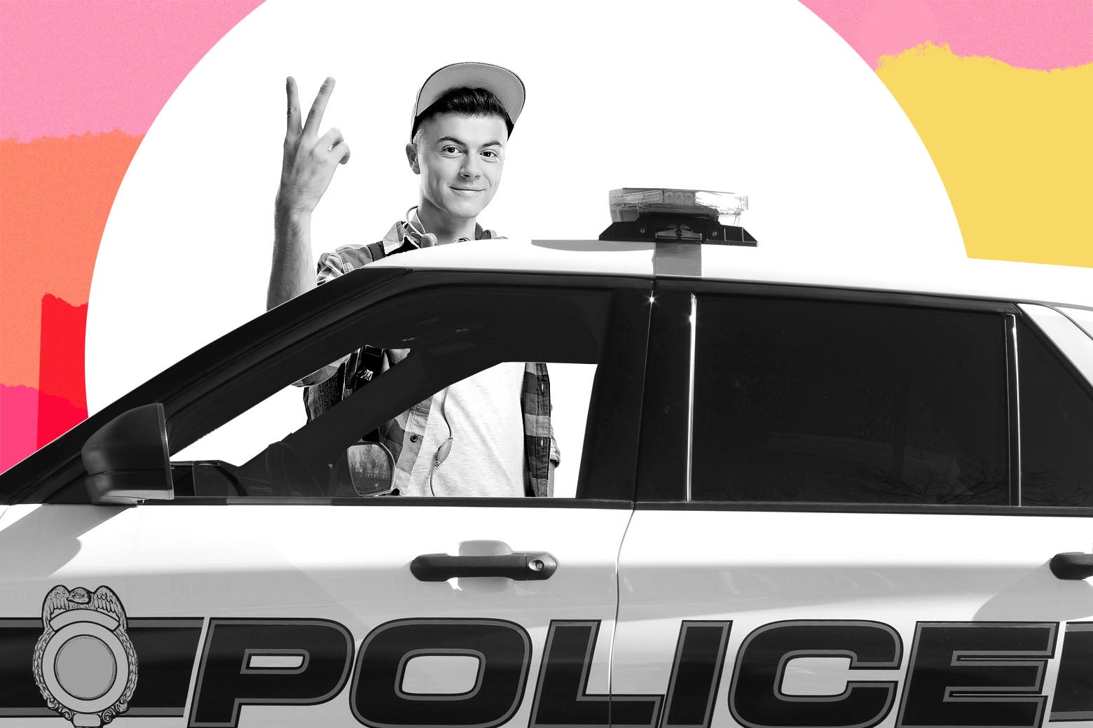 A teenager smiles and makes a peace sign as he stands next to a police car