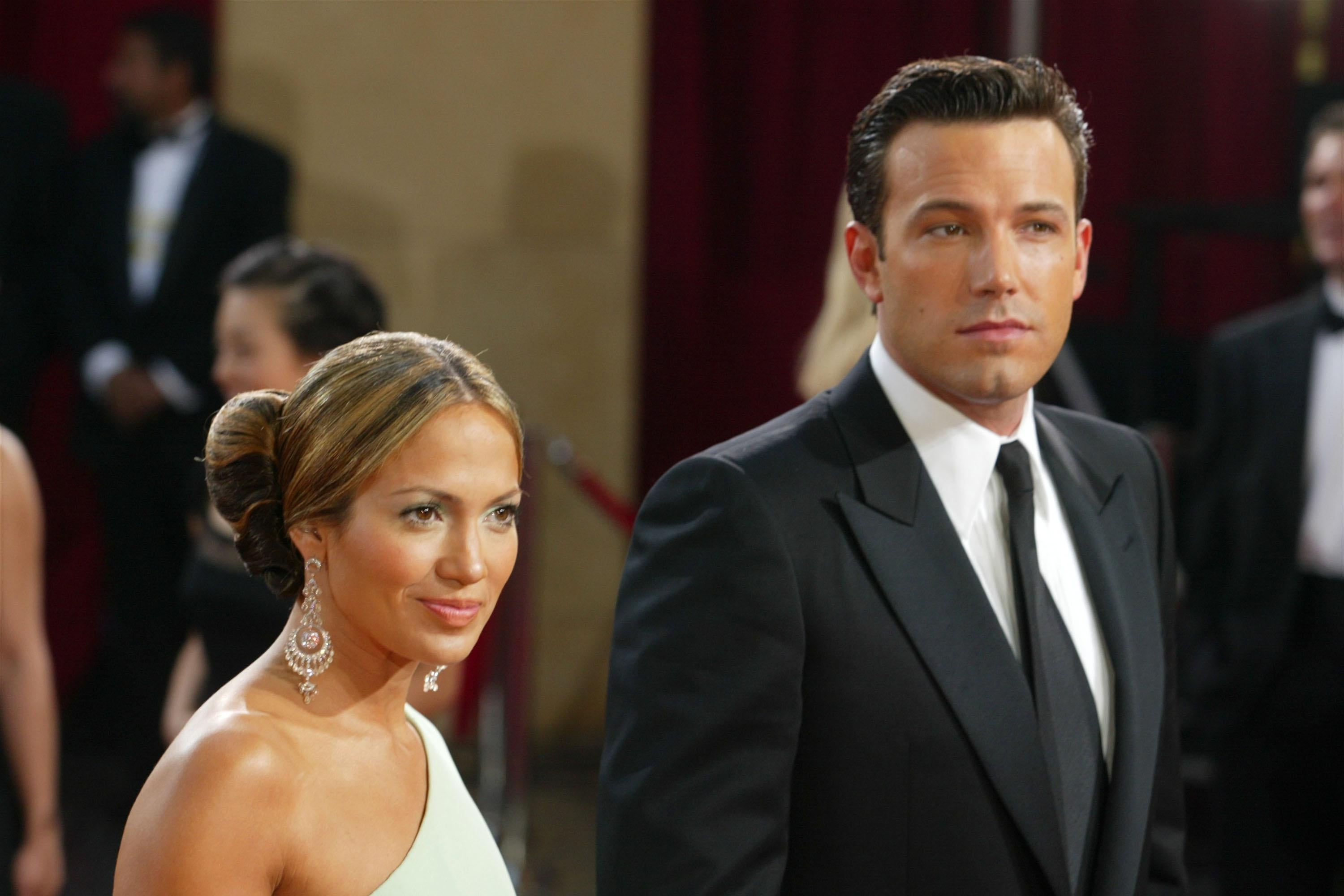 Jennifer Lopez in a one-shoulder white dress and Ben Affleck in a suit on the red carpet
