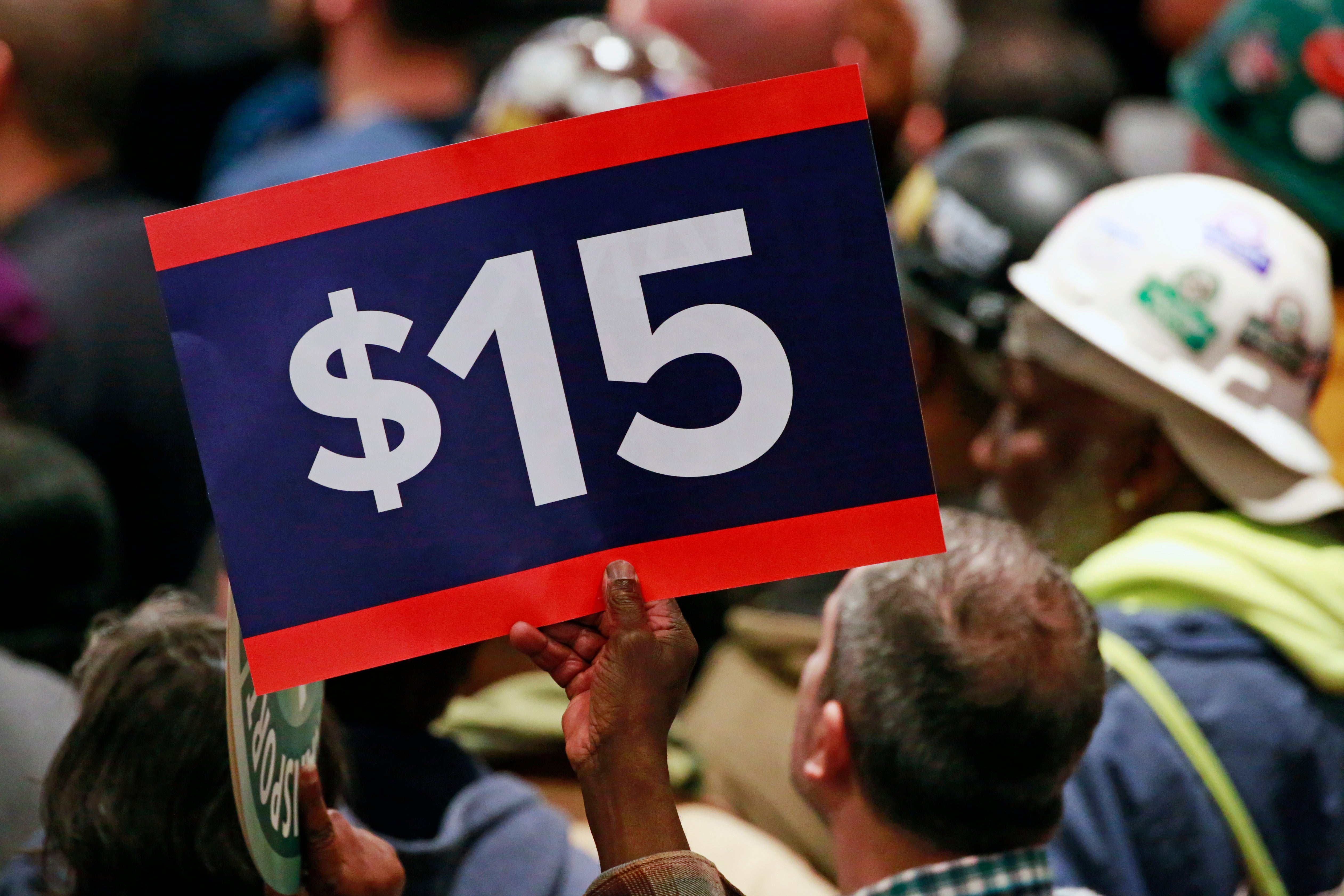 A worker holds up a sign demanding a $15 minimum wage