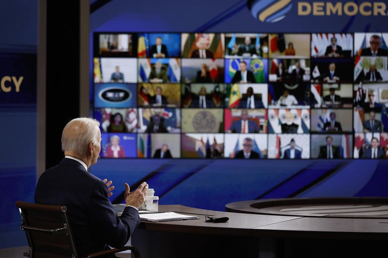 President Biden seated before a large screen showing a video call of heads of state.