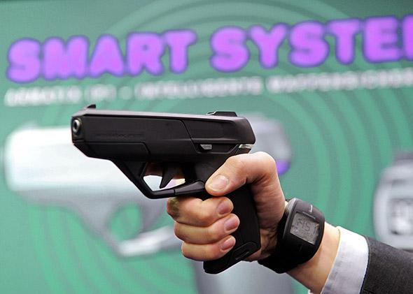 An employee of Armatix poses for photographers as he presents the SmartGun.