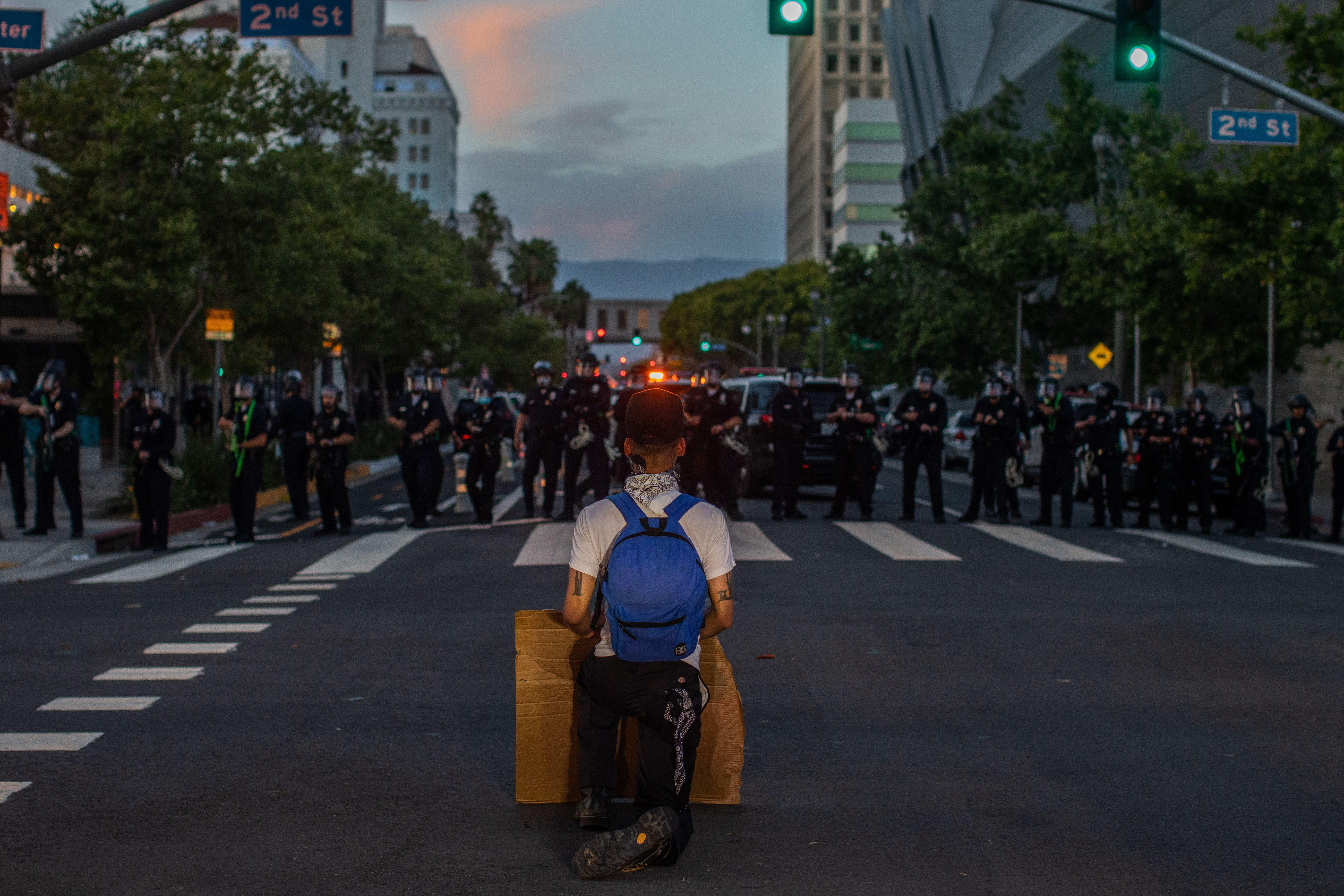A demonstrator kneels in front of a Police line in Downtown Los Angeles on May 30, 2020.
