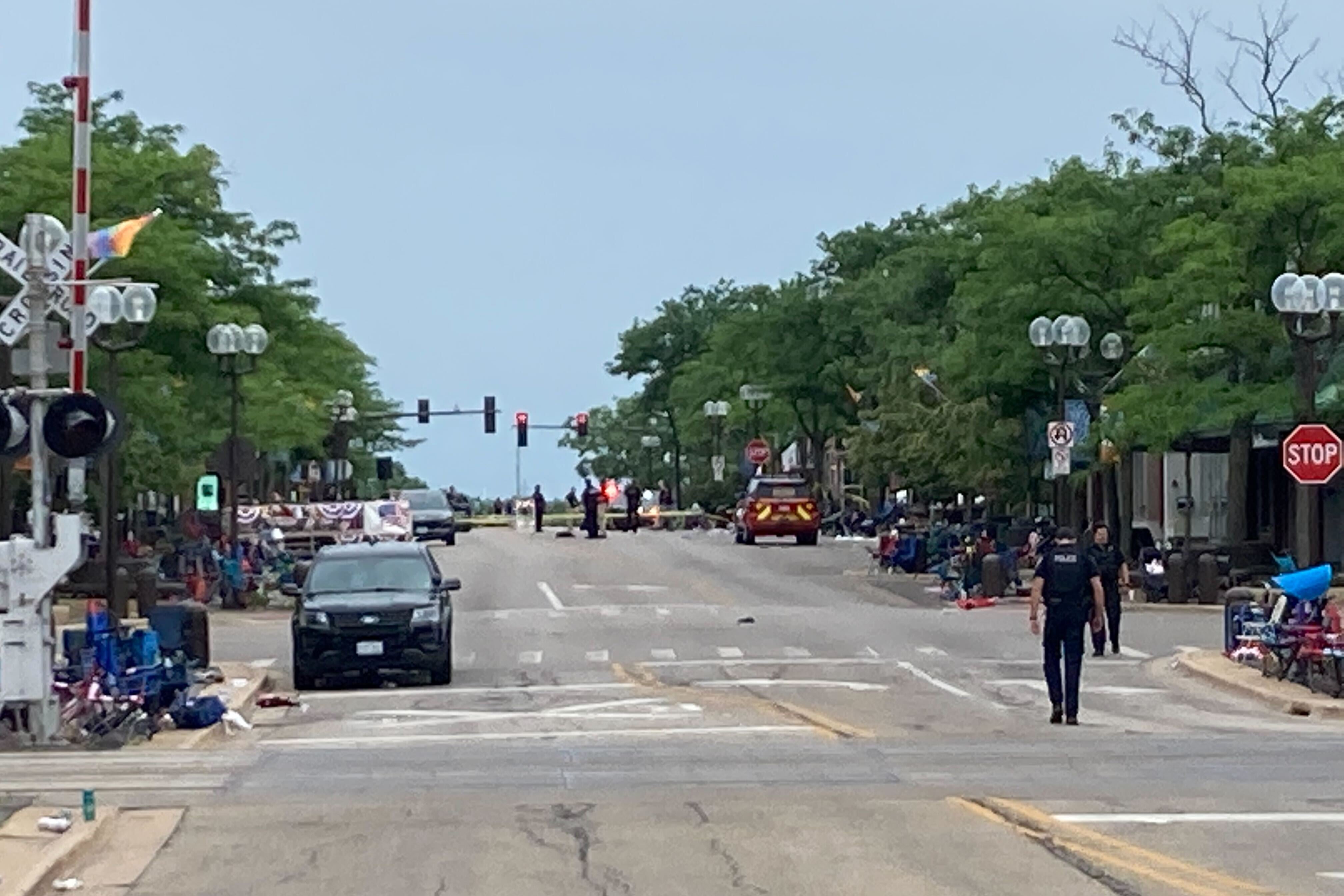 An empty street, littered with abandoned camping chairs and closed off with CAUTION tape.