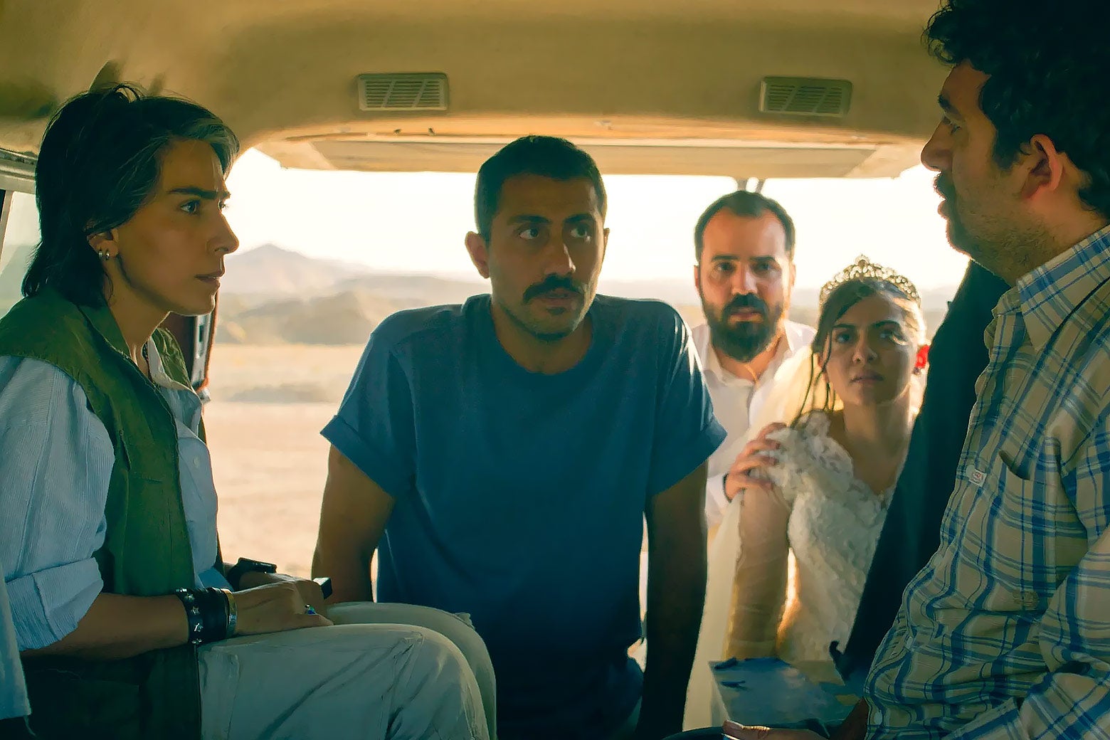 A group of people inside a van looking concerned at each other.