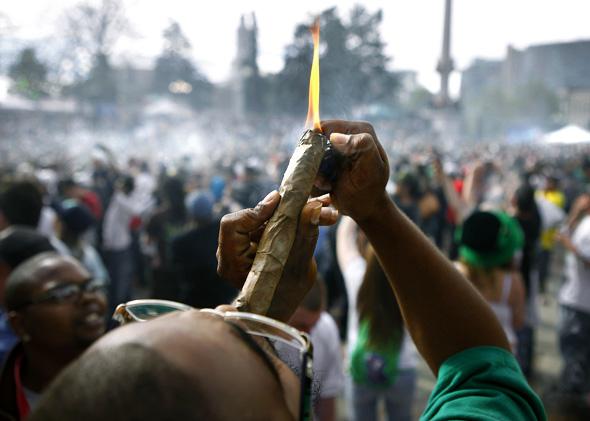 A person identifying himself as Jermagisty Tha King of Denver lights up a 28 ounce blunt at exactly 4:20 p.m. as thousands gathered to celebrate the state's medicinal marijuana laws.