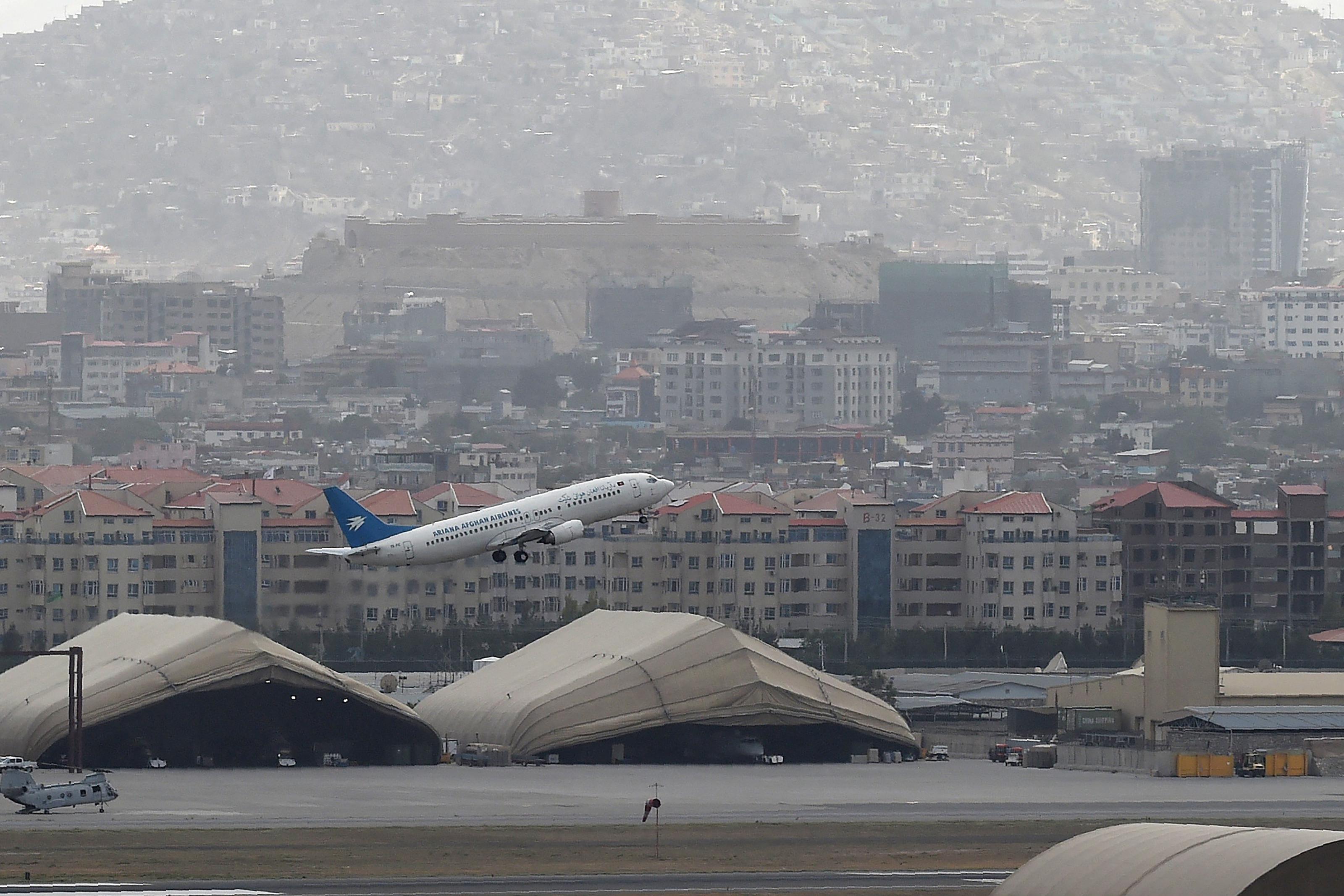 An Ariana Afghan Airlines plane takes off with the city of Kabul in the background