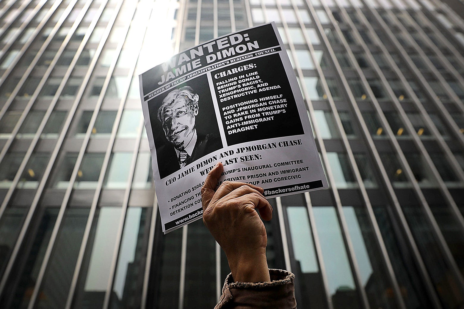 A mockup of a wanted poster for JPMorgan CEO Jamie Dimon is held outside his apartment in New York City.