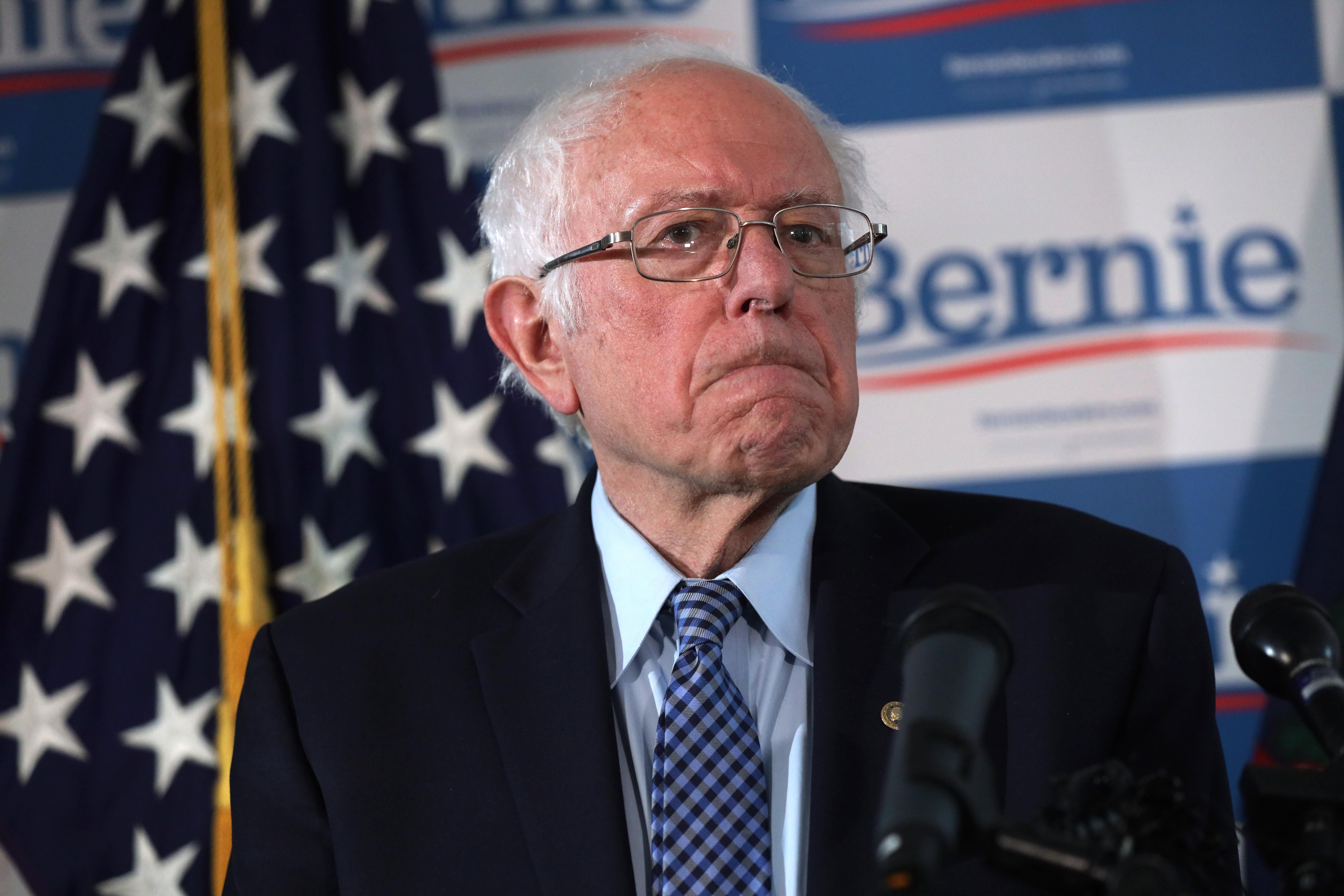 Bernie Sanders frowning in front of a mic
