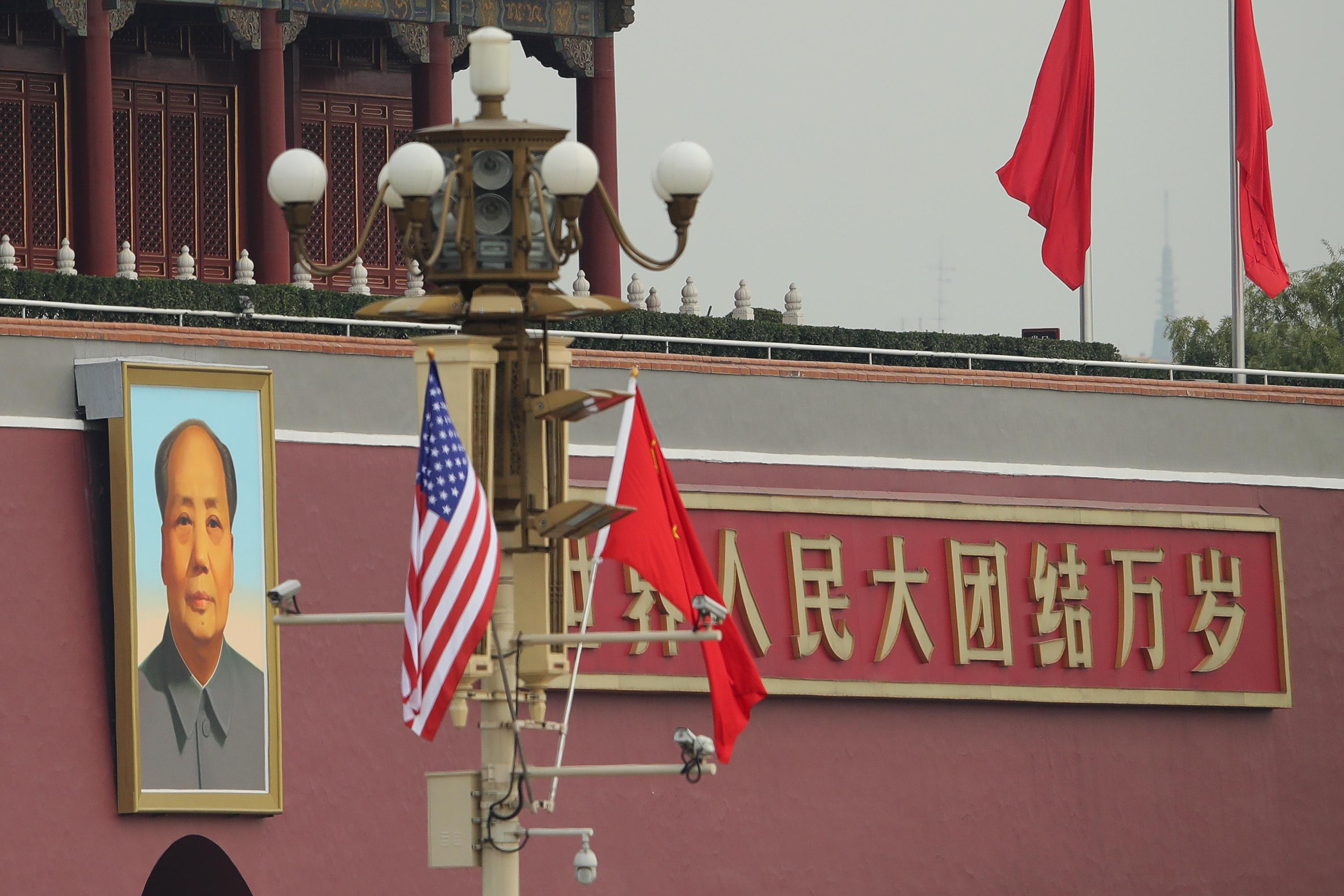A U.S. flag and a Chinese flag hang on a pole in front of the portrait of Mao Zedong outside the palace