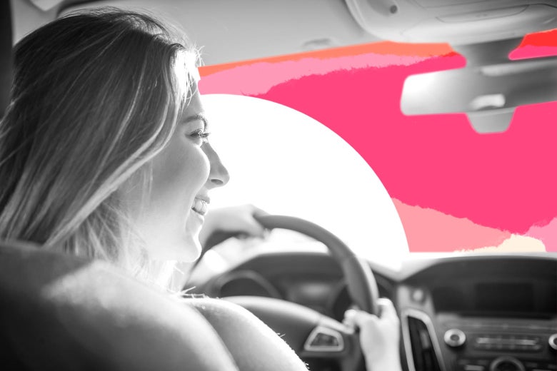 A teenage girl smiling behind the wheel of a car.