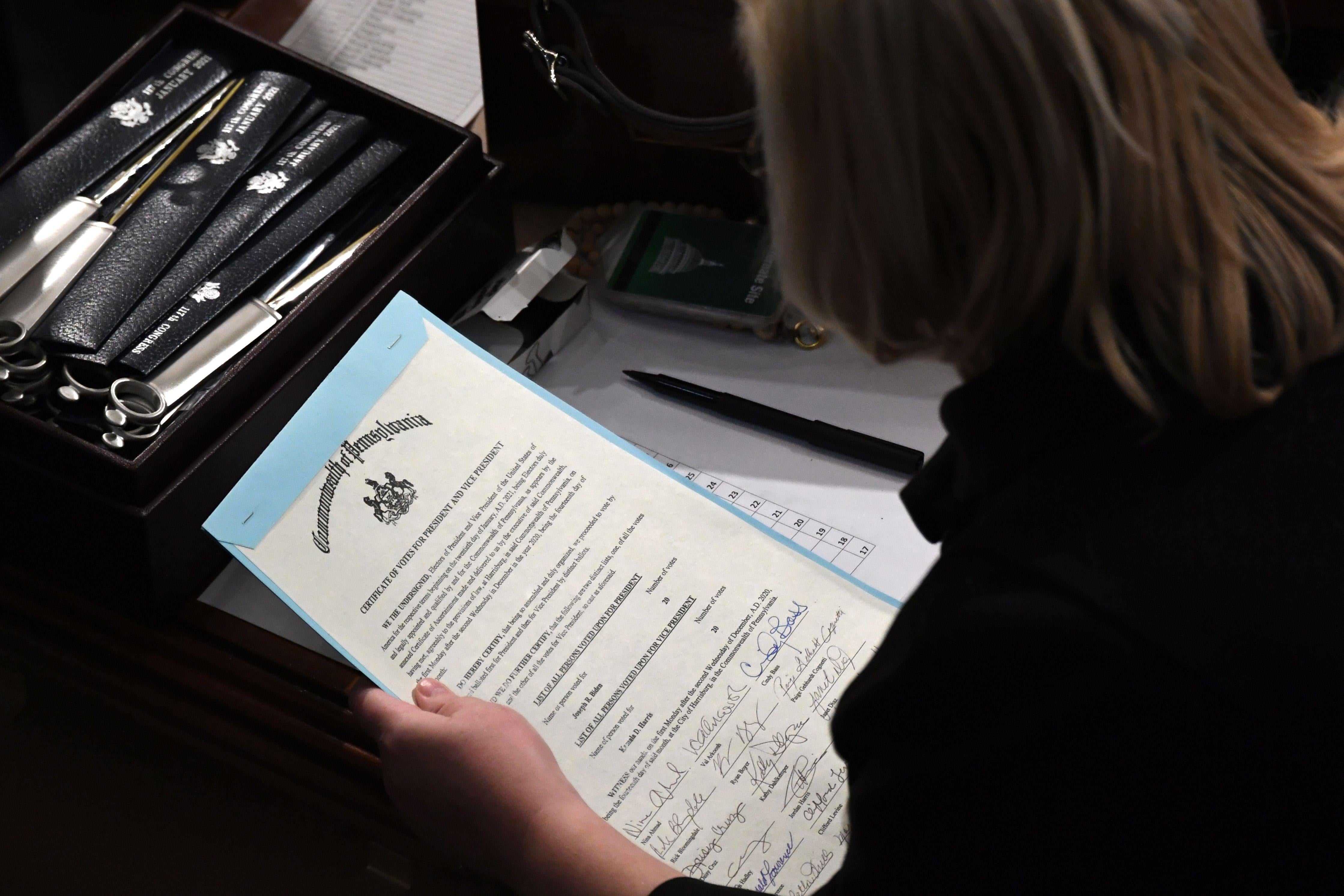 A person holds the certificate of votes from the Commonwealth of Pennsylvania above a desk