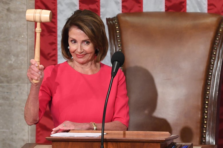 Pelosi smiles as she holds a gavel above a lectern