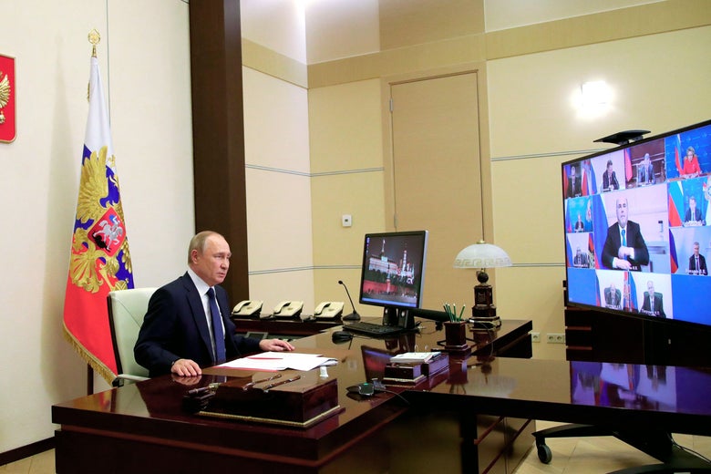 Putin sitting in front of a TV with a bunch of different faces.