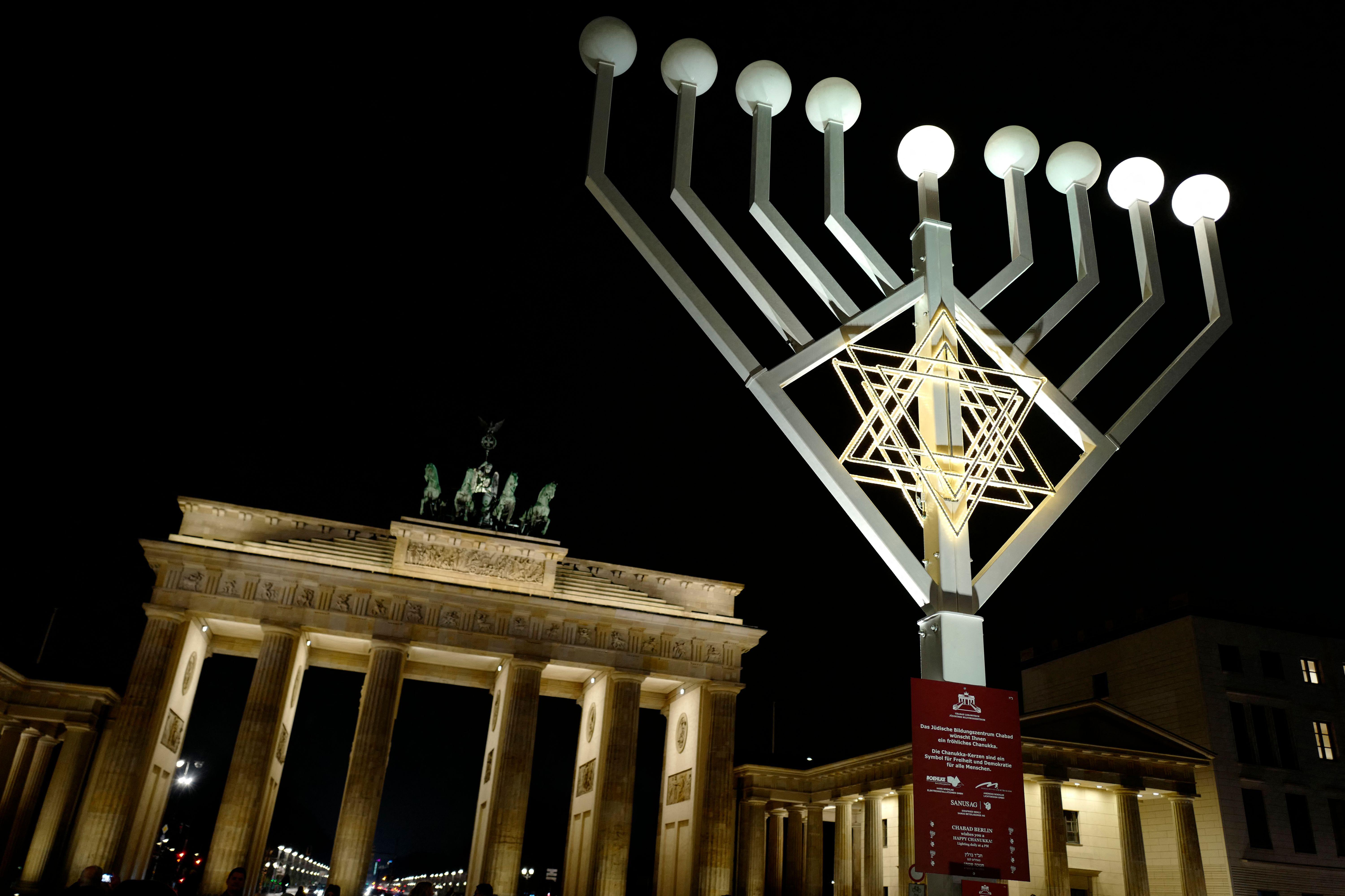 A large menorah in front of the Brandenburg Gate at nighttime.
