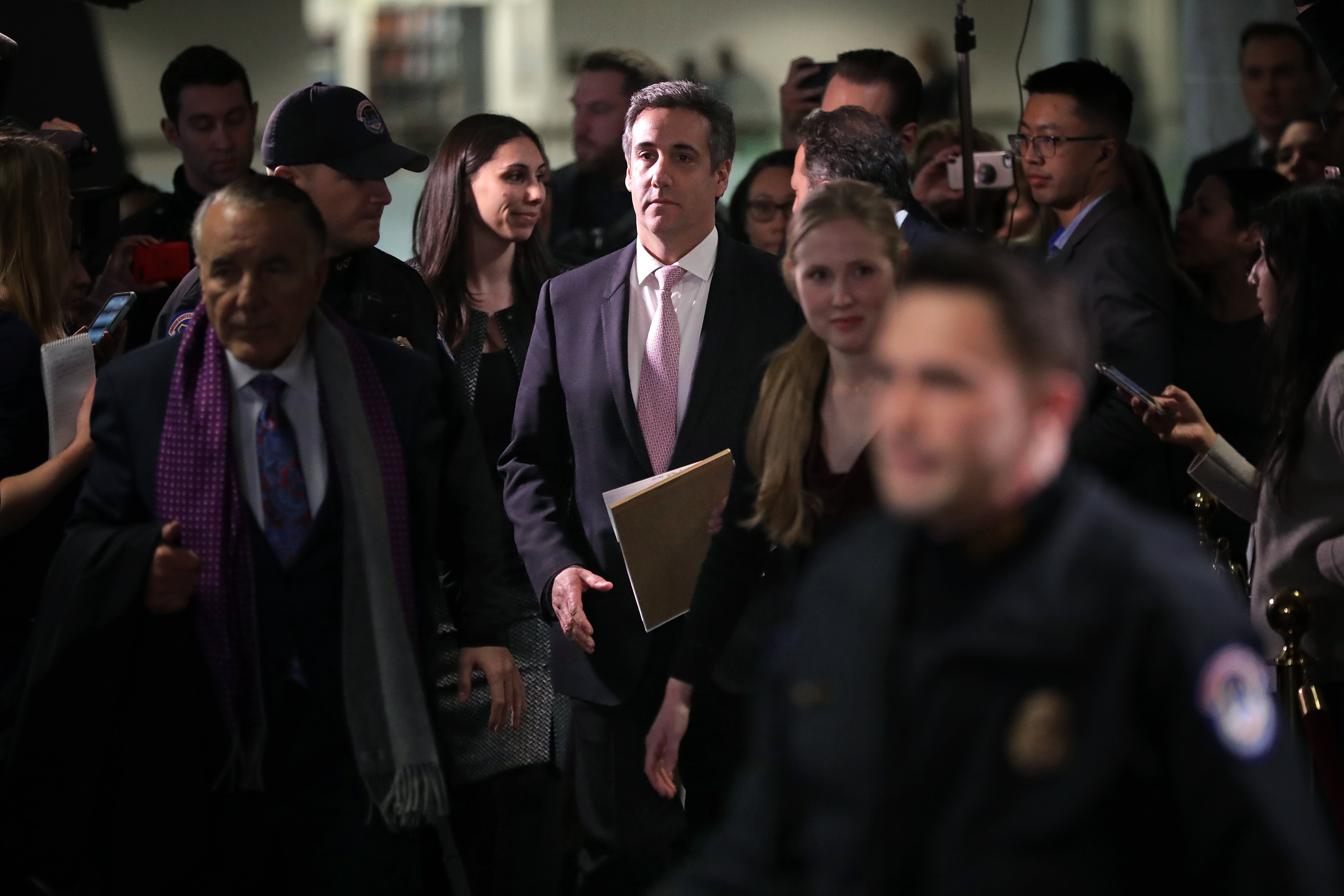 Cohen, walking, is surrounded by a crowd of people.