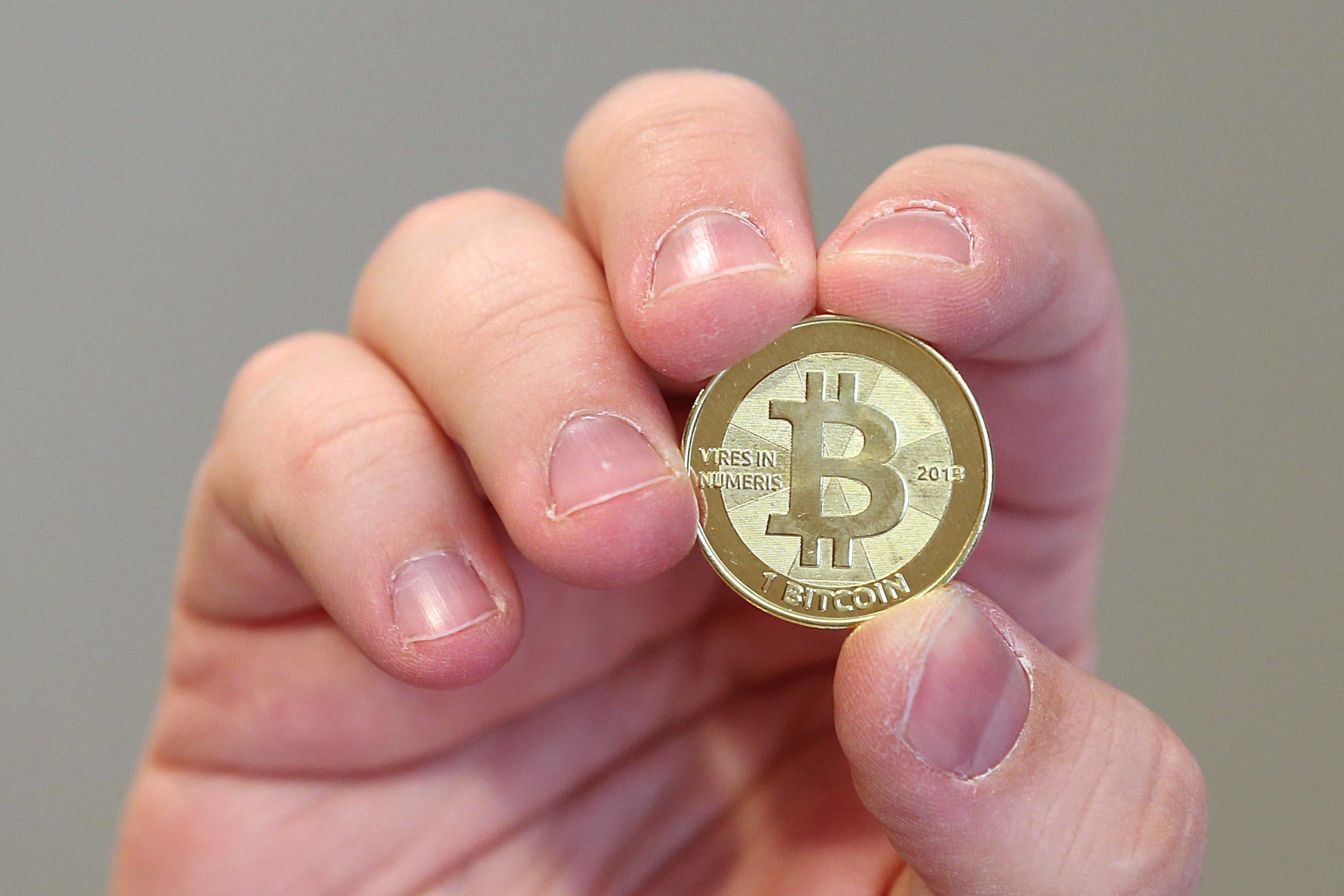 A hand holding a physical Bitcoin.