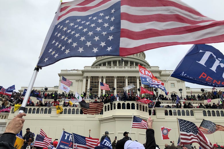 People rioting on the west side of the Capitol with Trump flags