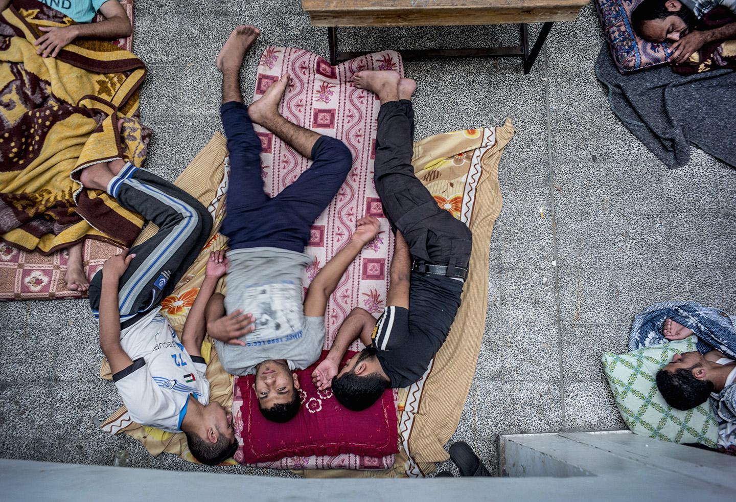 Palestinian men rest as dozens of displaced families.