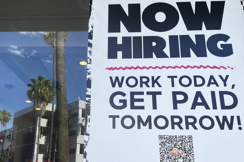 A sign that says "Now Hiring, Work Today, Get Paid Tomorrow" in the window of a Del Taco in Los Angeles
