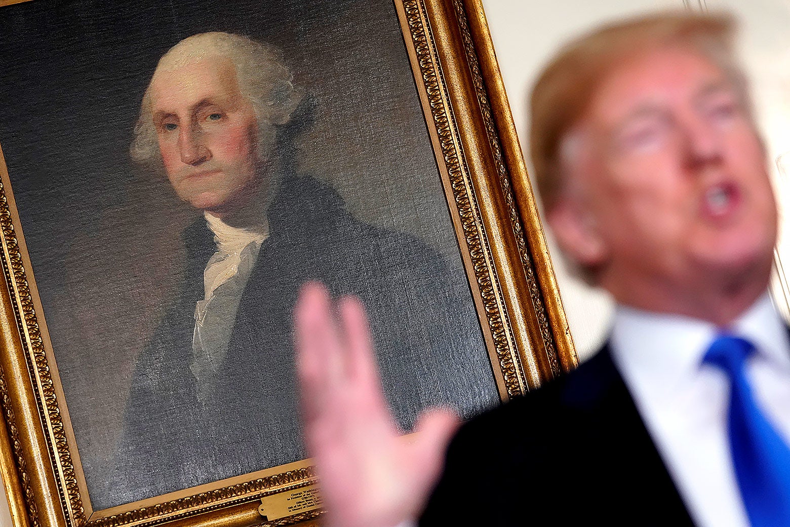 A portrait of George Washington, behind Donald Trump.