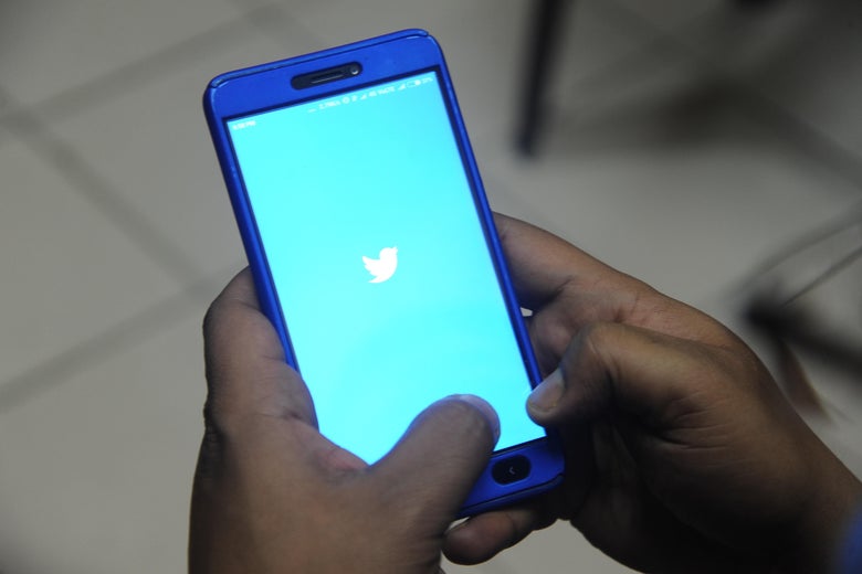 A man poses for a photograph using Twitter on his cellphone.