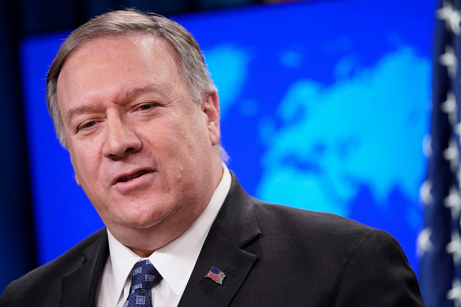Pompeo tilts his head while speaking. He is wearing a visible American flag pin on his lapel.