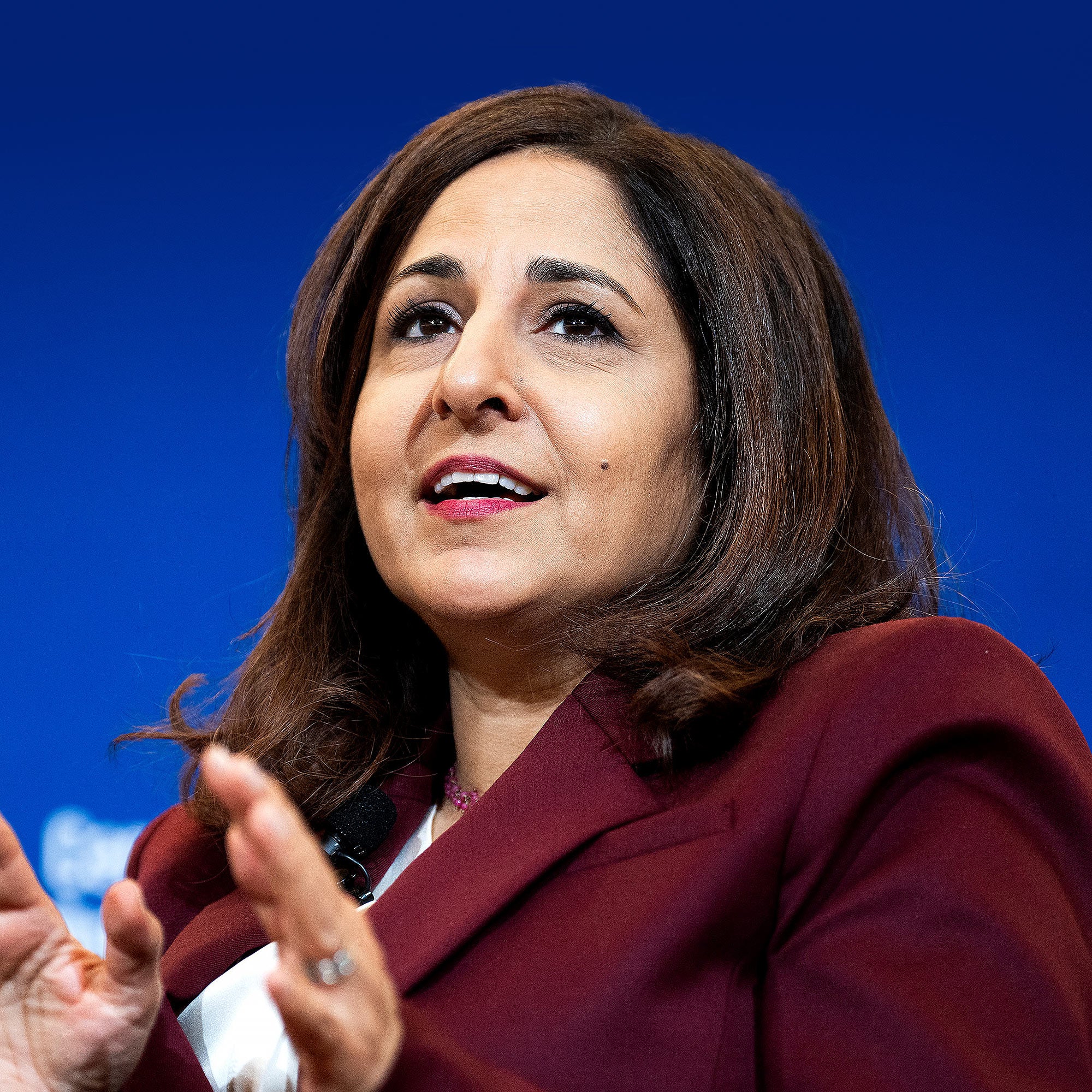 Neera Tanden in a red suit with her mouth open to speak.