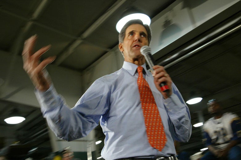 John Kerry, viewed from below, gestures while holding a microphone.