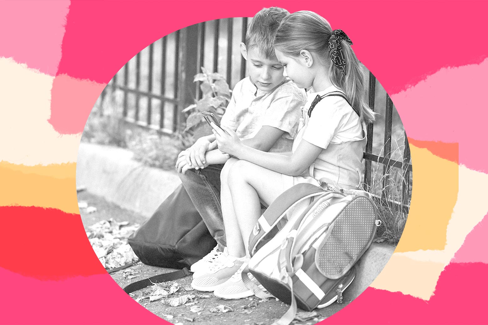 Two kids with backpacks sitting together in front of a gate.