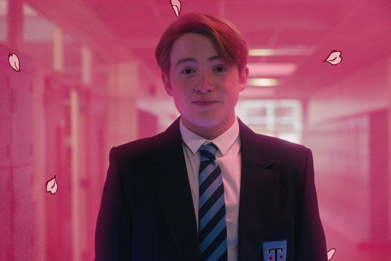 A teenage boy in a school blazer, surrounded by pink light and cartoon flower petals.