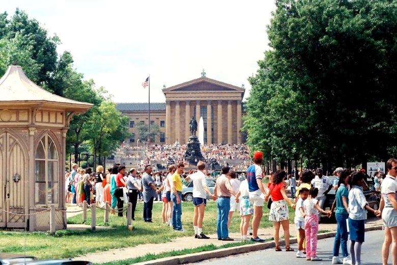 People hold hands in a line through a park in Philadelphia.