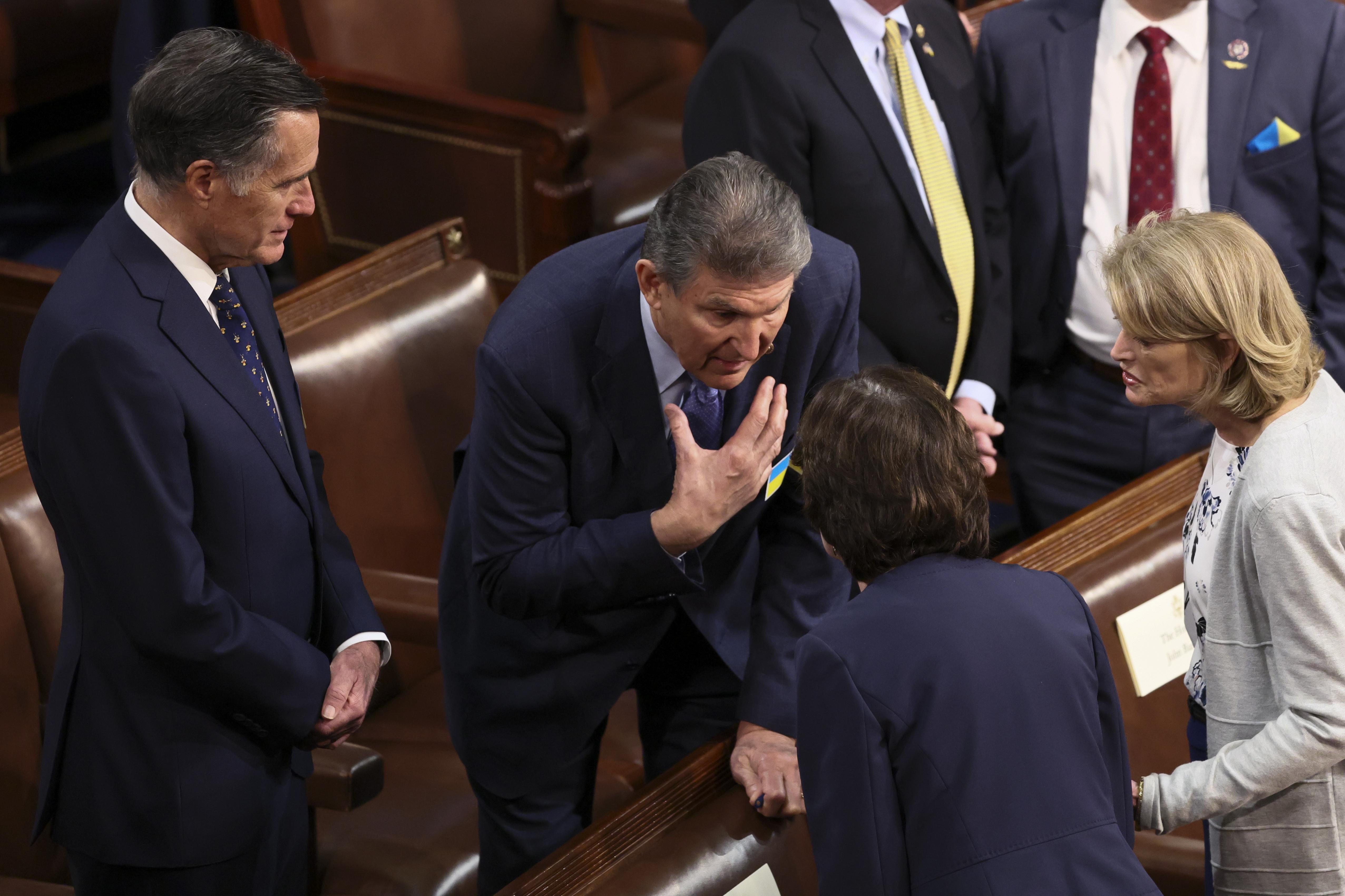 Manchin leans over to talk to Collins as Murkowski and Romney listen in.