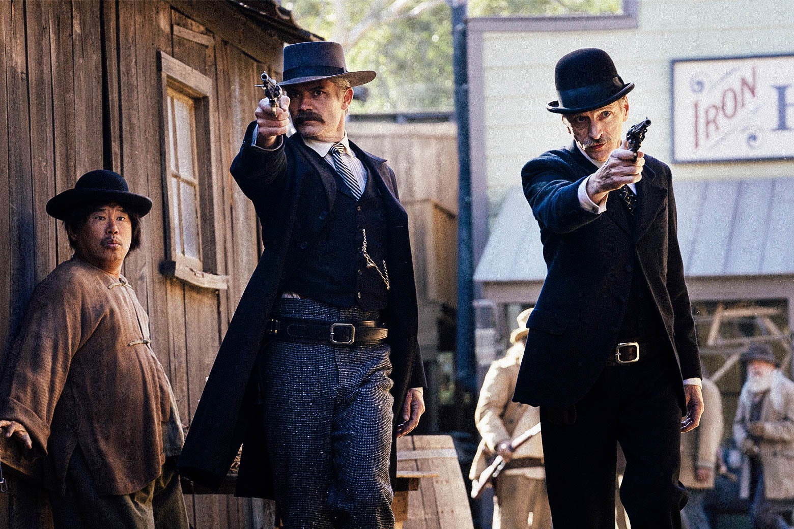 In a scene from Deadwood: The Movie, Timothy Olyphant and John Hawkes as Seth Bullock and Sol Star, aiming guns as they walk through town.