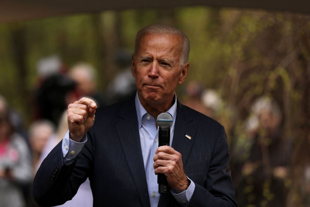 Biden, wearing a suit coat without a tie, speaks outdoors.