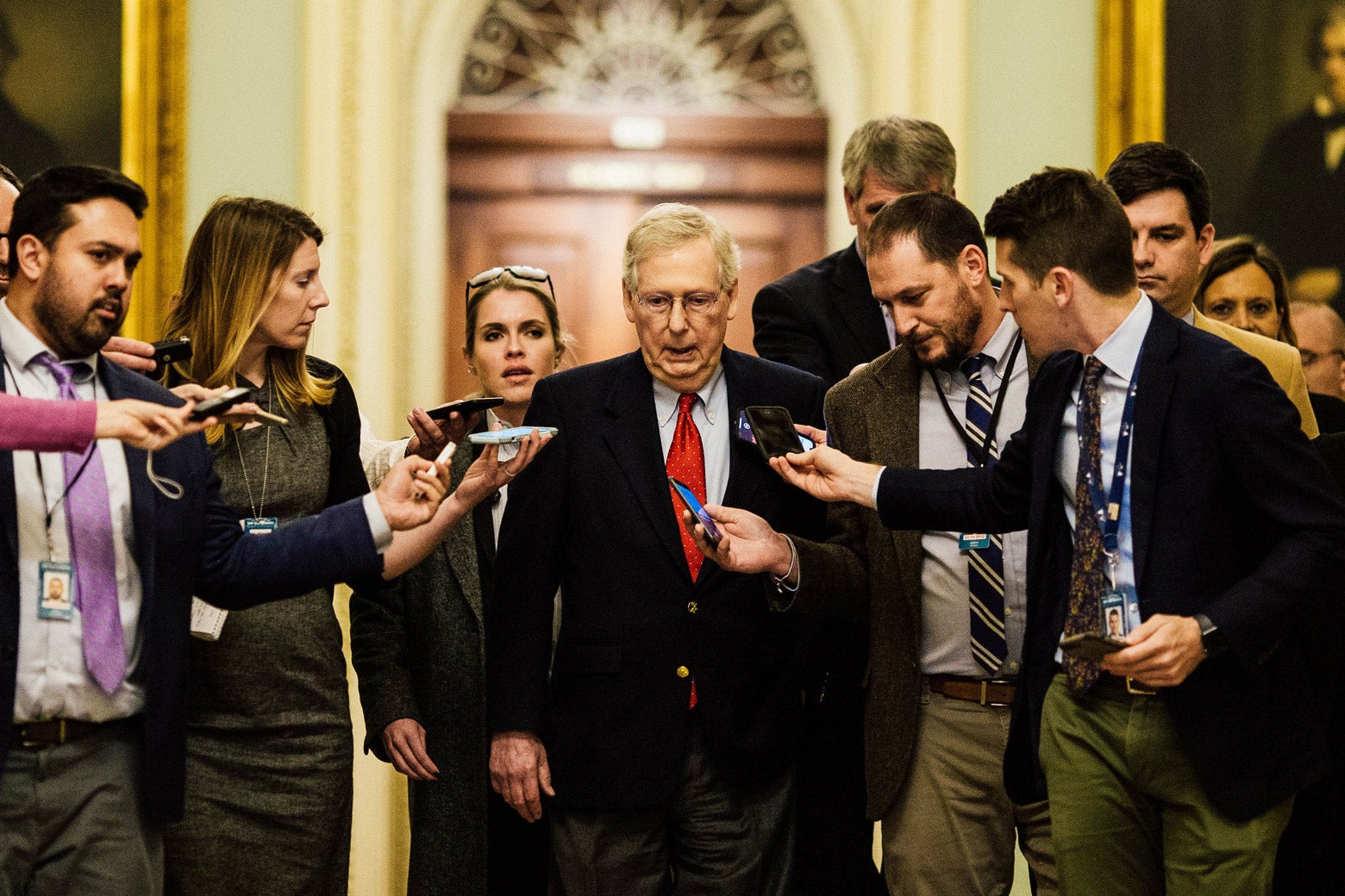 McConnell surrounded by reporters holding their phones out, trying to get a quote from him.