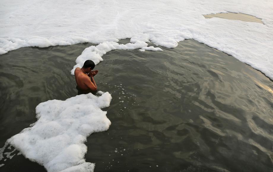 An Indian Hindu devotee prays in a polluted section of the Yamuna River, holy to Hindus, on the outskirts of New Delhi, India, on March 10, 2013. Officials say factories are ignoring regulations and dumping untreated sewage and industrial pollution, turning toxic the river that gives the capital much of its drinking water.
