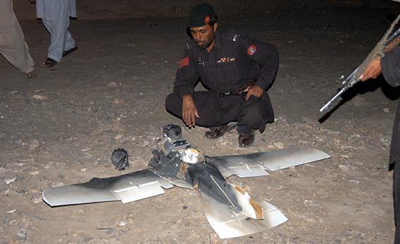 Pakistani security personnel examine a crashed American surveillance drone.