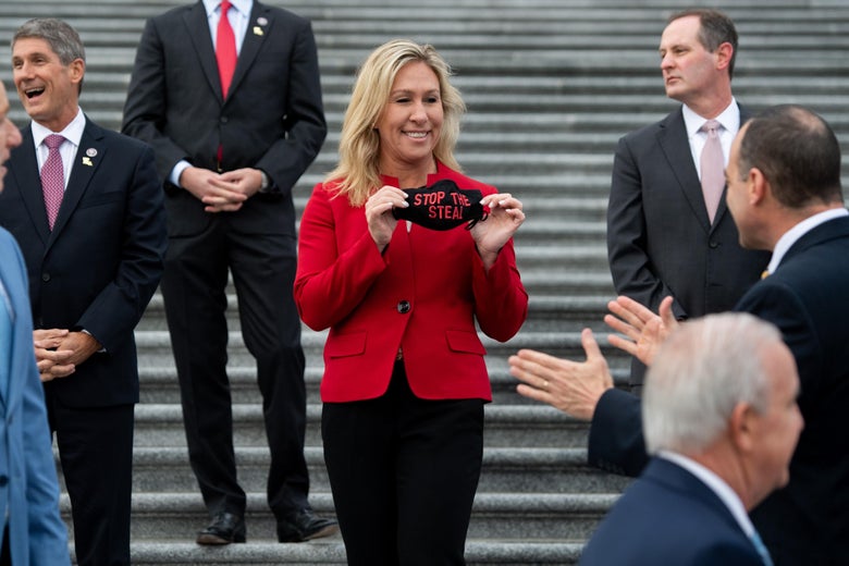 Greene shows off her "Stop the Steal" mask to other lawmakers on the steps of the Capitol.