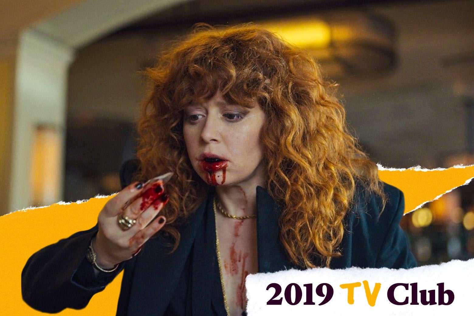Natasha Lyonne holds and stares at a shard of glass she just pulled out of her mouth. Her hand and mouth are bloody.