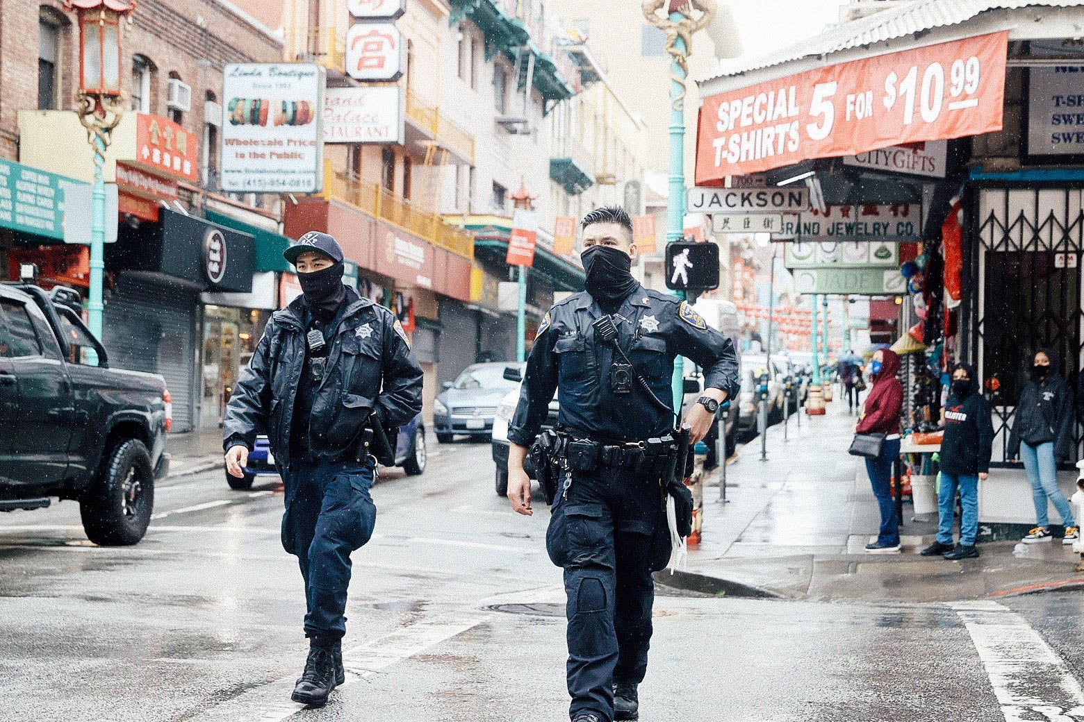Two police officers wearing black gaiters walk through Chinatown