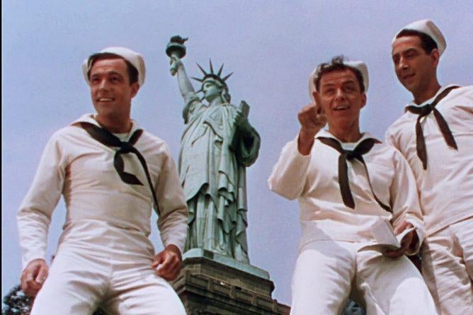 A still of Gene Kelly, Frank Sinatra, and Jules Munshin by the Statue of Liberty in On the Town.