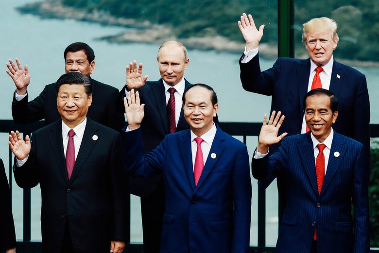 President Donald Trump and other men in suits raise a hand in a wave.