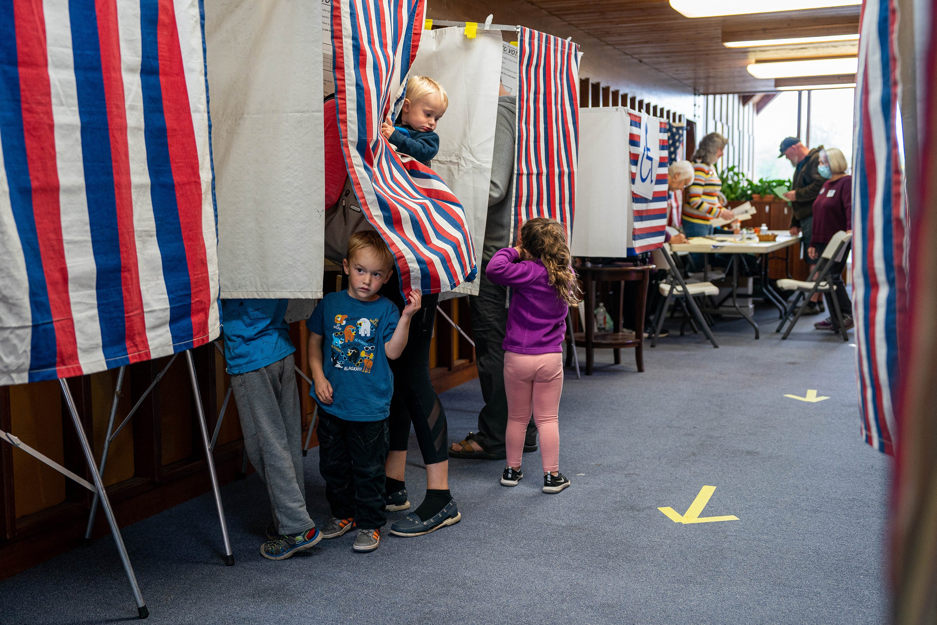 Two little boys peeking out from behind a voting curtain while their parent votes in Alaska's special election for the state's one seat in the House of Representatives, in August.